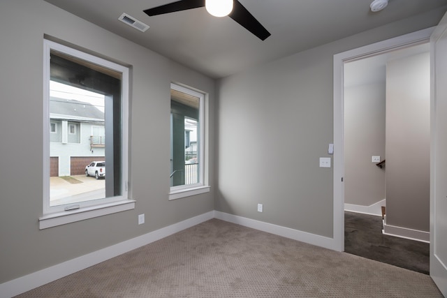 spare room with dark colored carpet and ceiling fan