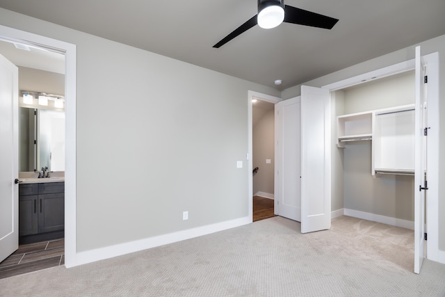 unfurnished bedroom featuring a closet, light carpet, ceiling fan, sink, and connected bathroom