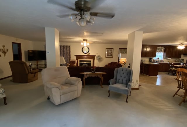 living area featuring ceiling fan and a fireplace