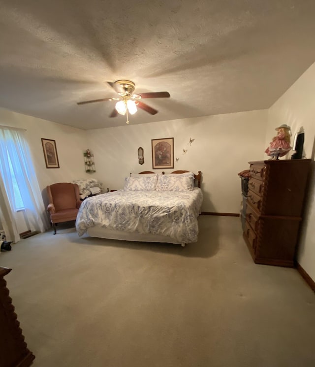 bedroom featuring baseboards, light colored carpet, a ceiling fan, and a textured ceiling