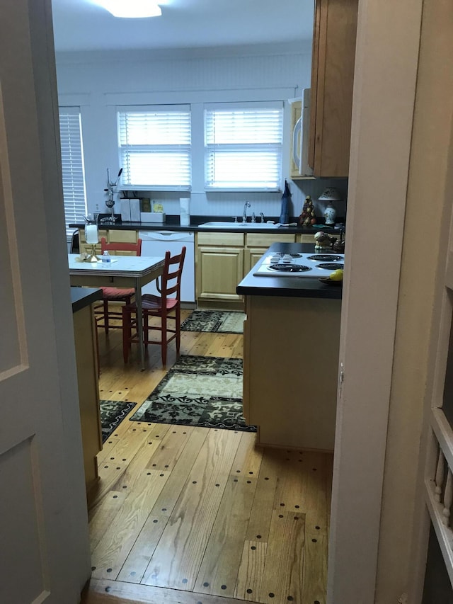 kitchen with white appliances, sink, a healthy amount of sunlight, and light wood-type flooring