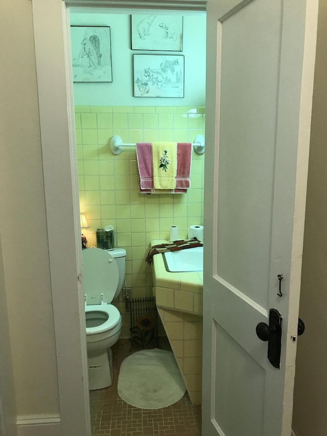 bathroom with tile walls, toilet, and tile floors