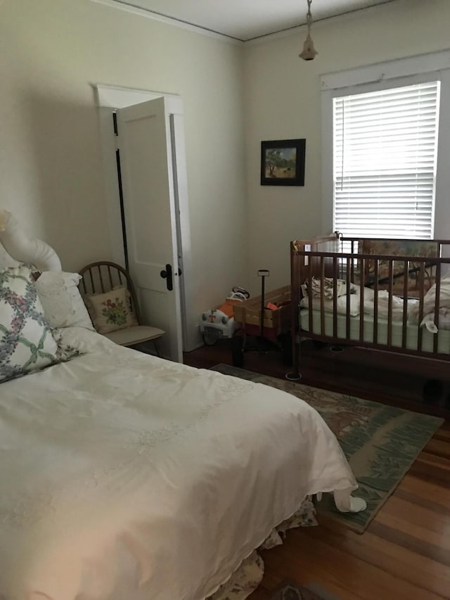 bedroom with ornamental molding and dark wood-type flooring