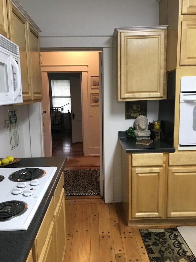 kitchen featuring light brown cabinets, light hardwood / wood-style floors, and white appliances