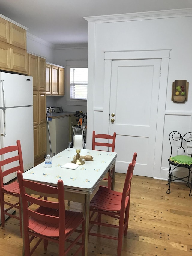 dining area featuring ornamental molding, light hardwood / wood-style flooring, and washer / dryer