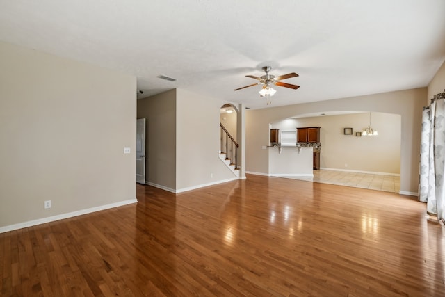 unfurnished living room with hardwood / wood-style flooring and ceiling fan with notable chandelier