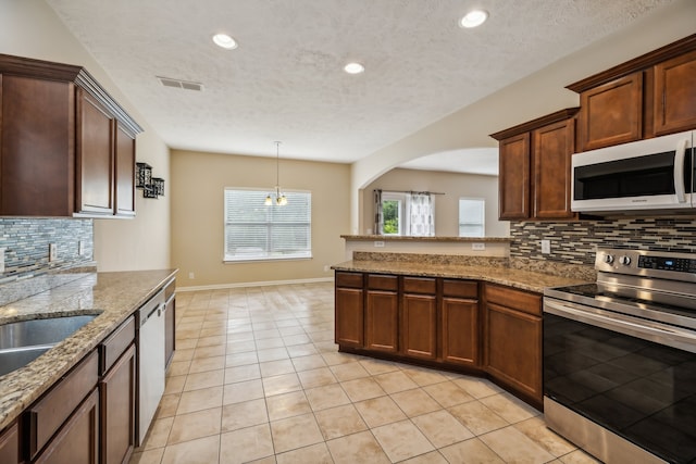 kitchen featuring backsplash, appliances with stainless steel finishes, light tile patterned floors, and a textured ceiling