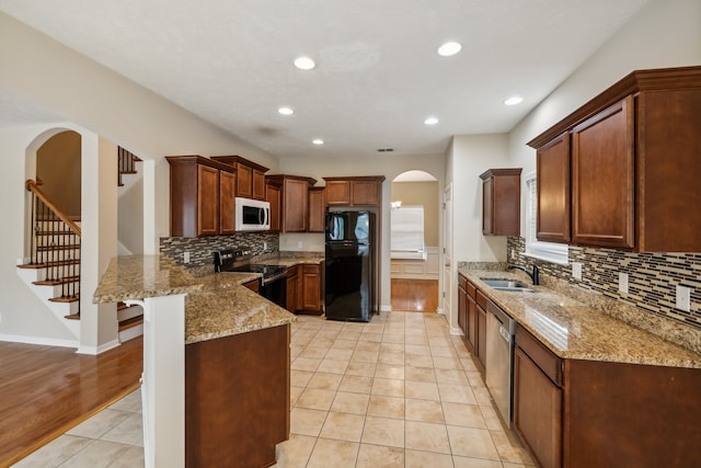 kitchen featuring kitchen peninsula, appliances with stainless steel finishes, sink, and light wood-type flooring