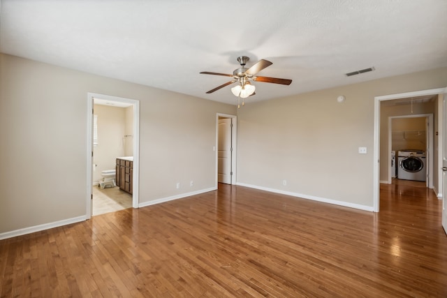 unfurnished room featuring independent washer and dryer, hardwood / wood-style flooring, and ceiling fan