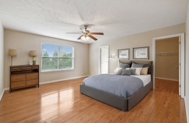 bedroom featuring ceiling fan, hardwood / wood-style floors, a spacious closet, a closet, and a textured ceiling