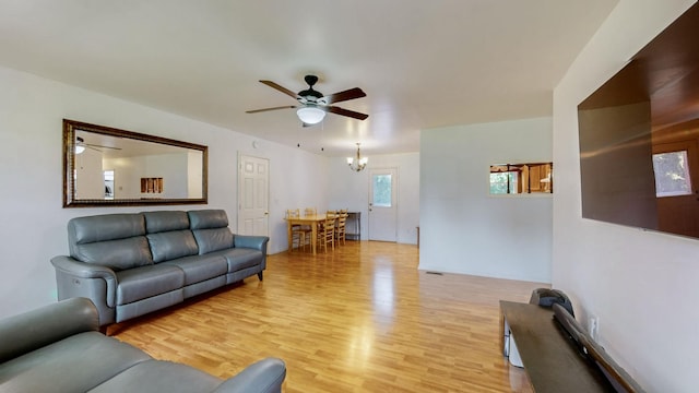 living room featuring ceiling fan with notable chandelier and light hardwood / wood-style floors