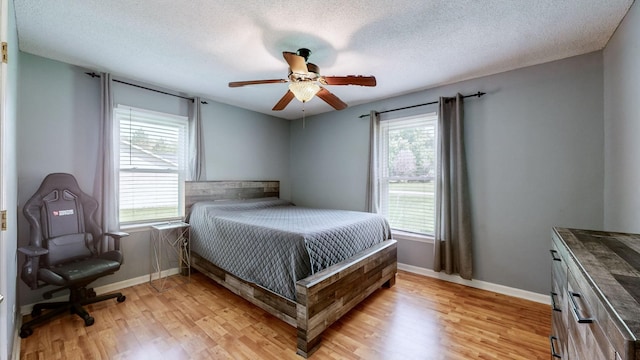 bedroom with ceiling fan, a textured ceiling, and light hardwood / wood-style flooring