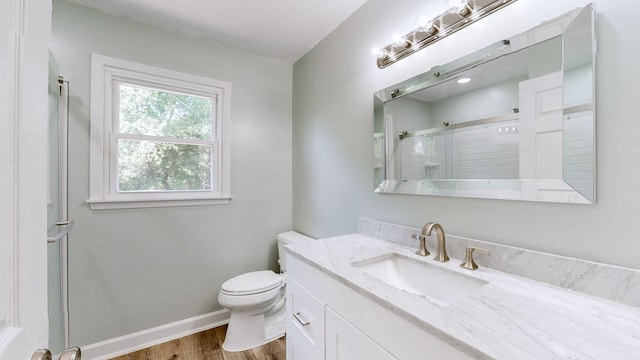 bathroom featuring vanity, hardwood / wood-style flooring, a shower with shower door, and toilet