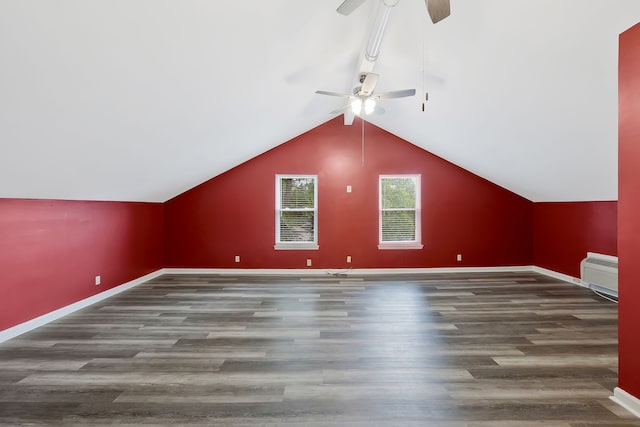 additional living space with an AC wall unit, ceiling fan, vaulted ceiling, and dark wood-type flooring