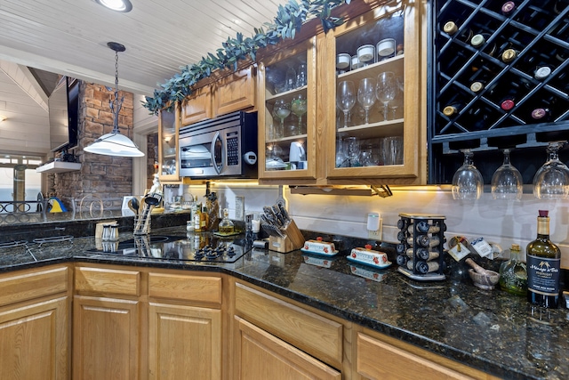 kitchen featuring glass insert cabinets, brown cabinets, stainless steel microwave, black electric cooktop, and pendant lighting