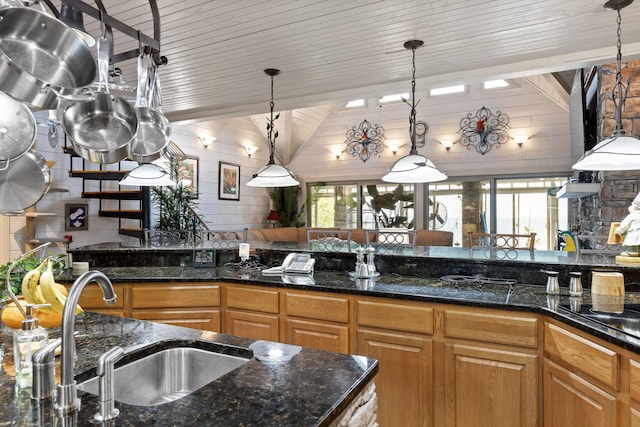 kitchen with hanging light fixtures, dark stone counters, and a sink