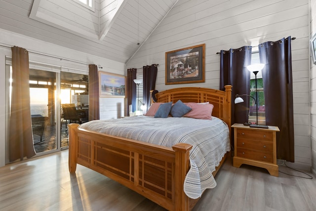 bedroom featuring lofted ceiling, wood walls, and wood finished floors