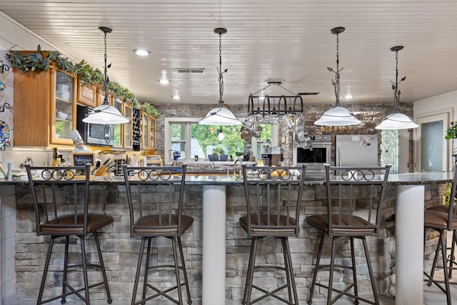 kitchen featuring hanging light fixtures, stainless steel appliances, glass insert cabinets, and a kitchen breakfast bar