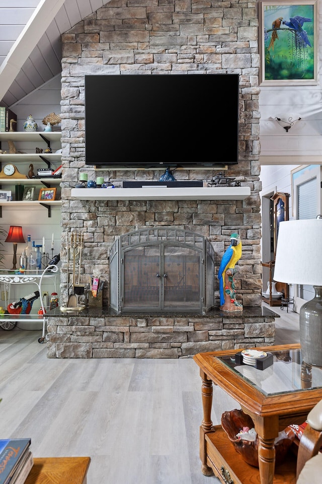 living room featuring a fireplace, vaulted ceiling, and wood finished floors