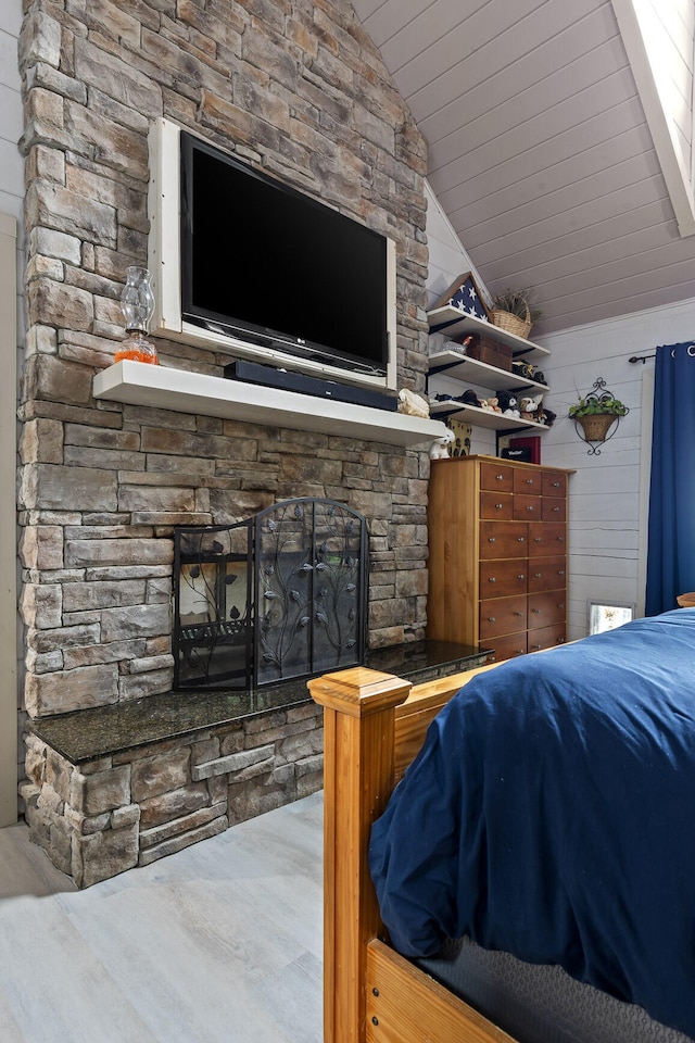 bedroom with lofted ceiling, wood ceiling, a fireplace, and wood walls