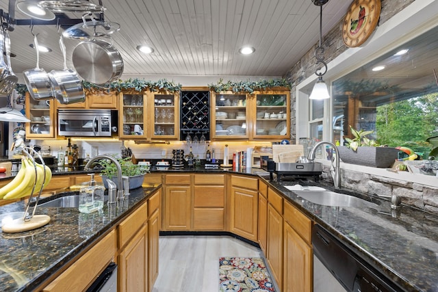 kitchen featuring glass insert cabinets, stainless steel appliances, a sink, and decorative light fixtures