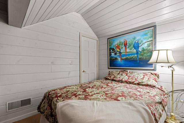 bedroom featuring lofted ceiling, wood walls, wood ceiling, and visible vents