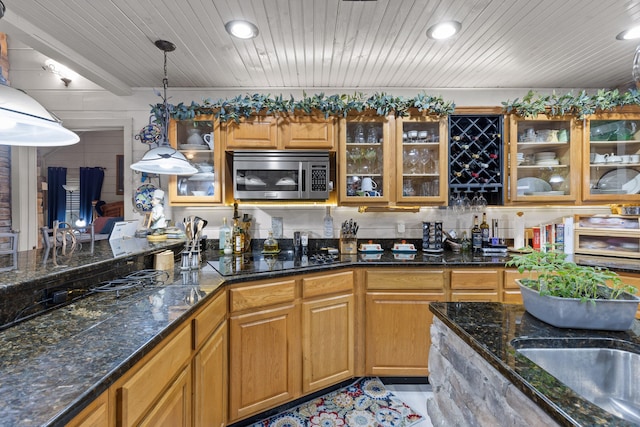 kitchen with wooden ceiling, glass insert cabinets, stainless steel microwave, black electric stovetop, and pendant lighting