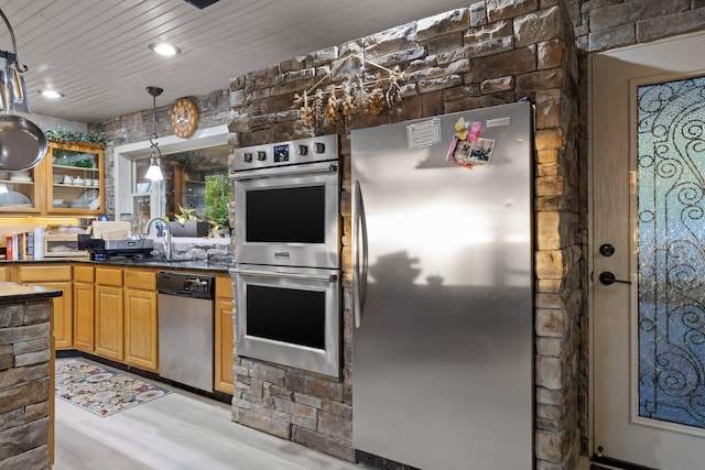 kitchen featuring dark countertops, wood ceiling, hanging light fixtures, stainless steel appliances, and a sink