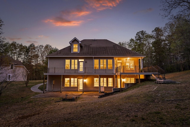 back house at dusk with a patio, a wooden deck, and a yard