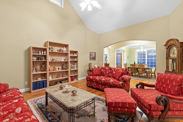 living room featuring high vaulted ceiling, ceiling fan with notable chandelier, and hardwood / wood-style floors