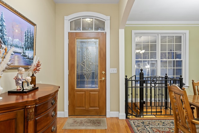 entryway featuring ornamental molding and light hardwood / wood-style floors