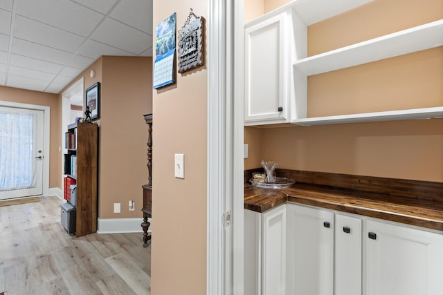 hall featuring a drop ceiling and light hardwood / wood-style flooring