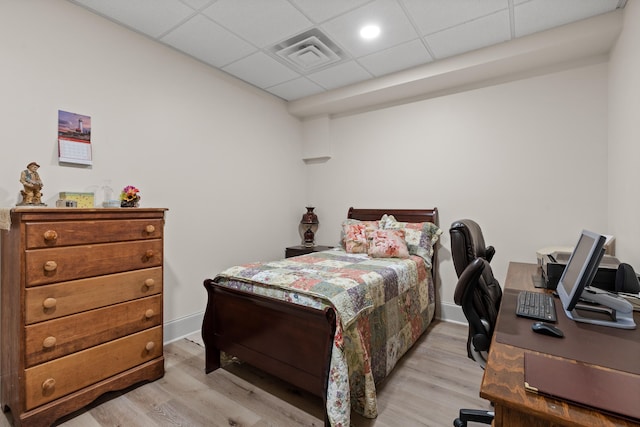 bedroom featuring a drop ceiling and light wood-type flooring