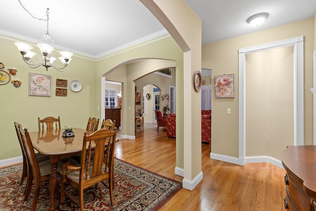 dining area with light hardwood / wood-style floors, ornamental molding, and a chandelier