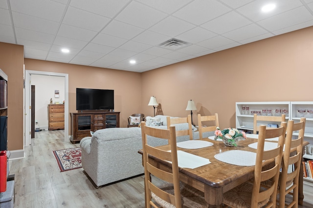 dining space with a drop ceiling and light hardwood / wood-style floors