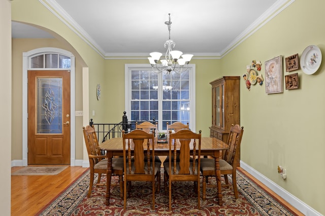 dining room featuring a notable chandelier, ornamental molding, and hardwood / wood-style floors