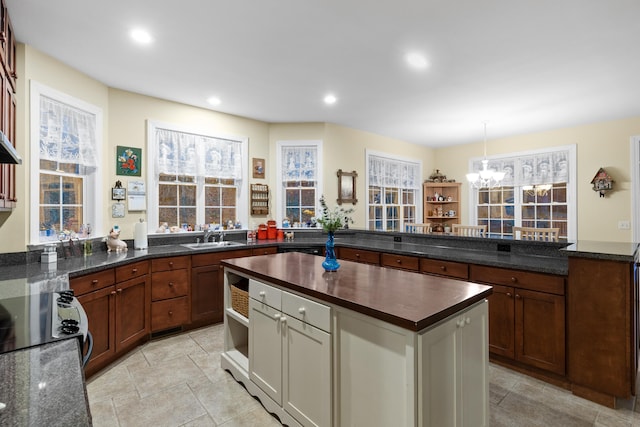 kitchen with hanging light fixtures, dark stone counters, sink, stove, and a chandelier