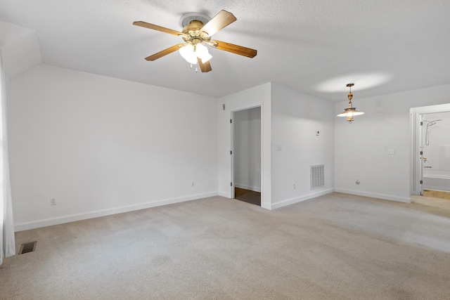 empty room with a textured ceiling, light colored carpet, and ceiling fan