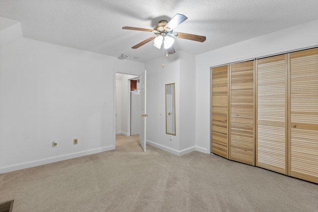 unfurnished bedroom with a closet, ceiling fan, a textured ceiling, and light colored carpet