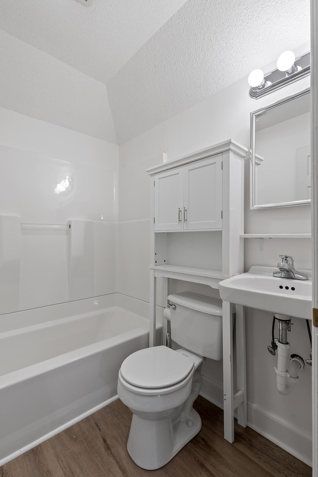 bathroom featuring shower / bathing tub combination, a textured ceiling, toilet, vaulted ceiling, and hardwood / wood-style flooring