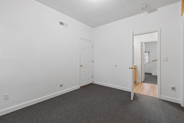 unfurnished bedroom featuring dark colored carpet and a textured ceiling