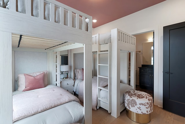 bedroom with ensuite bathroom and hardwood / wood-style flooring