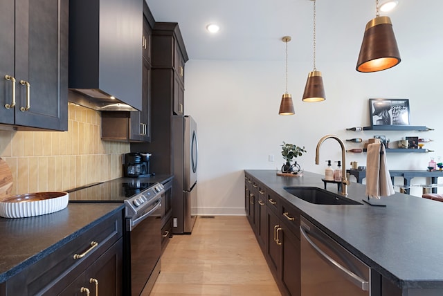 kitchen featuring stainless steel appliances, decorative backsplash, sink, light hardwood / wood-style flooring, and wall chimney range hood