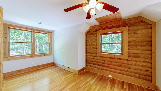 bonus room featuring light hardwood / wood-style floors, rustic walls, lofted ceiling, and ceiling fan