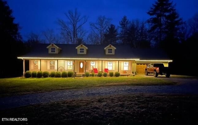 cape cod home featuring a garage, a yard, and a porch