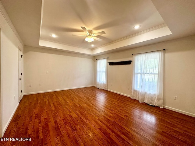 empty room featuring ceiling fan, a raised ceiling, ornamental molding, and hardwood / wood-style flooring