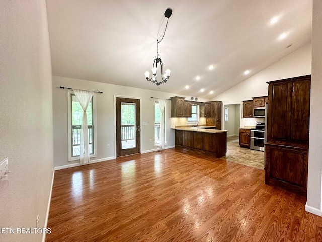 kitchen featuring appliances with stainless steel finishes, decorative light fixtures, light wood-type flooring, and a chandelier