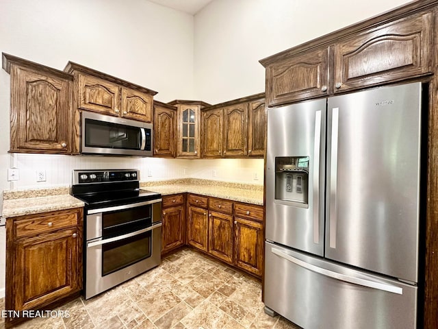 kitchen featuring stainless steel appliances, light stone counters, and light tile patterned floors