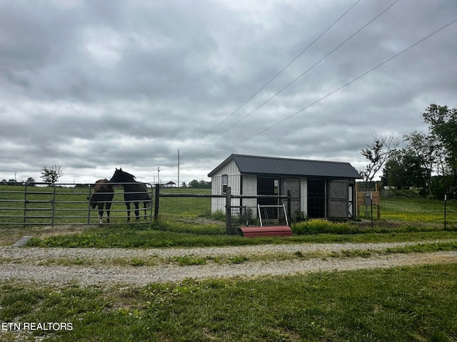 exterior space featuring an outbuilding, a rural view, and a lawn