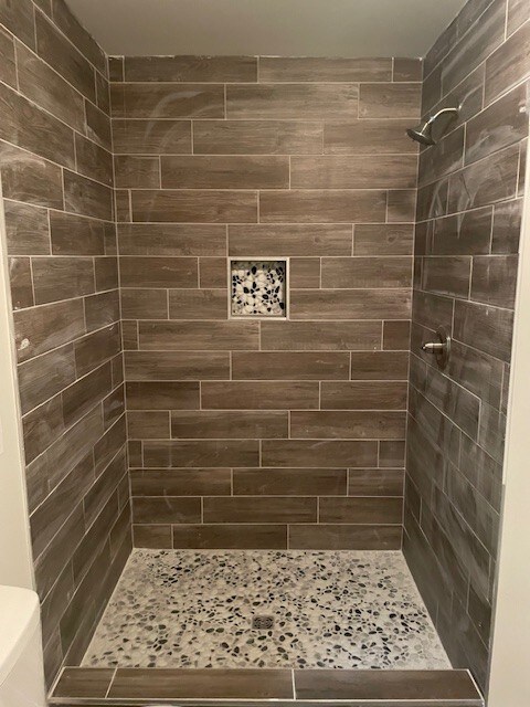 bathroom with toilet and a tile shower